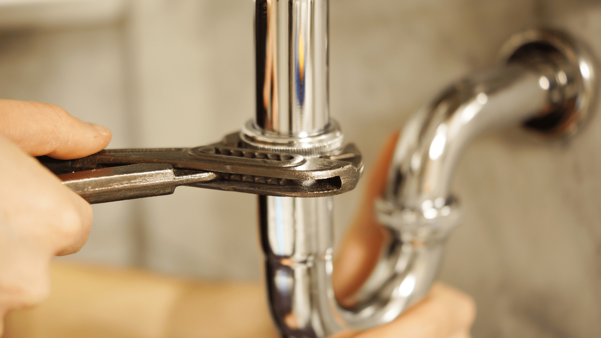 person using a wrench to repair plumbing