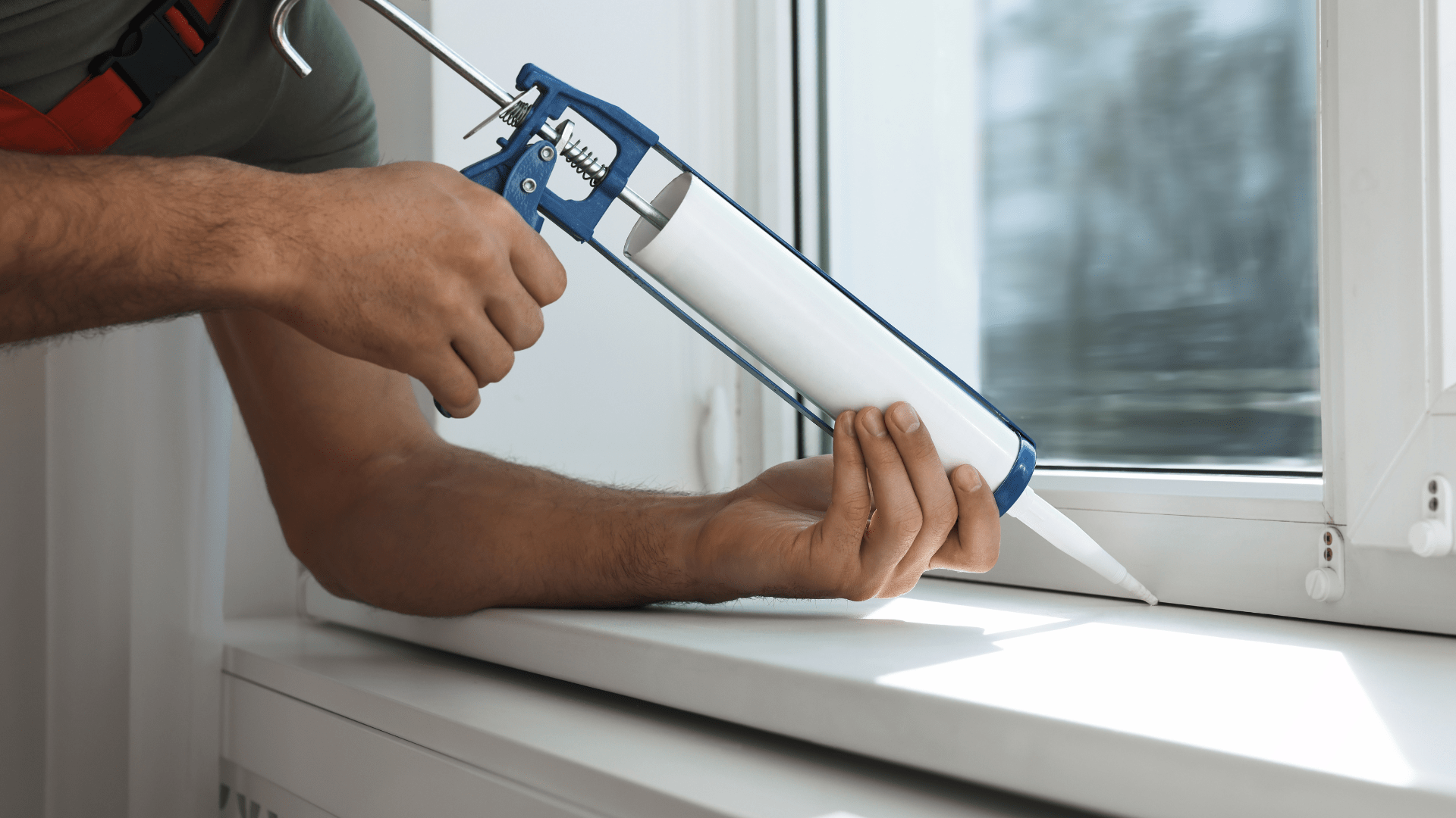 Person sealing a window to prep for winter