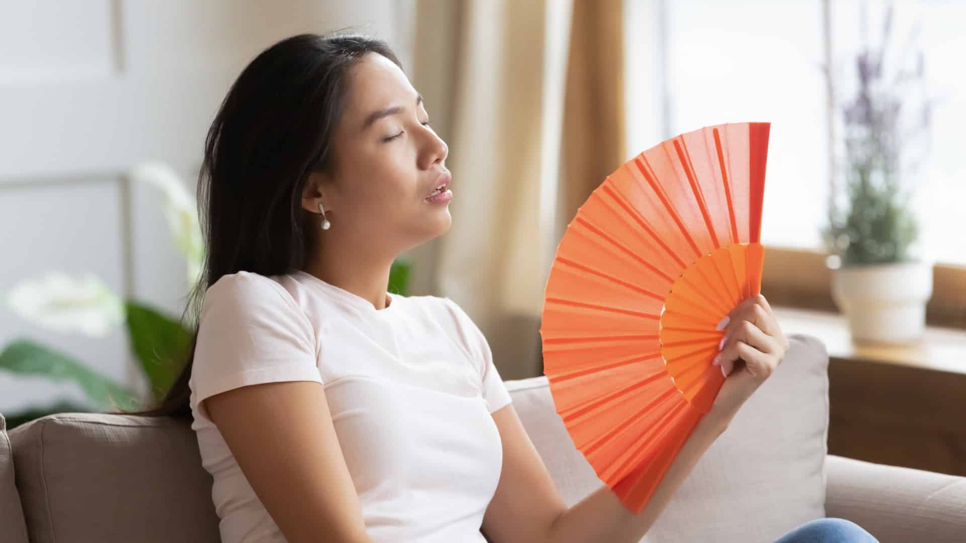 woman using fan to stay cool
