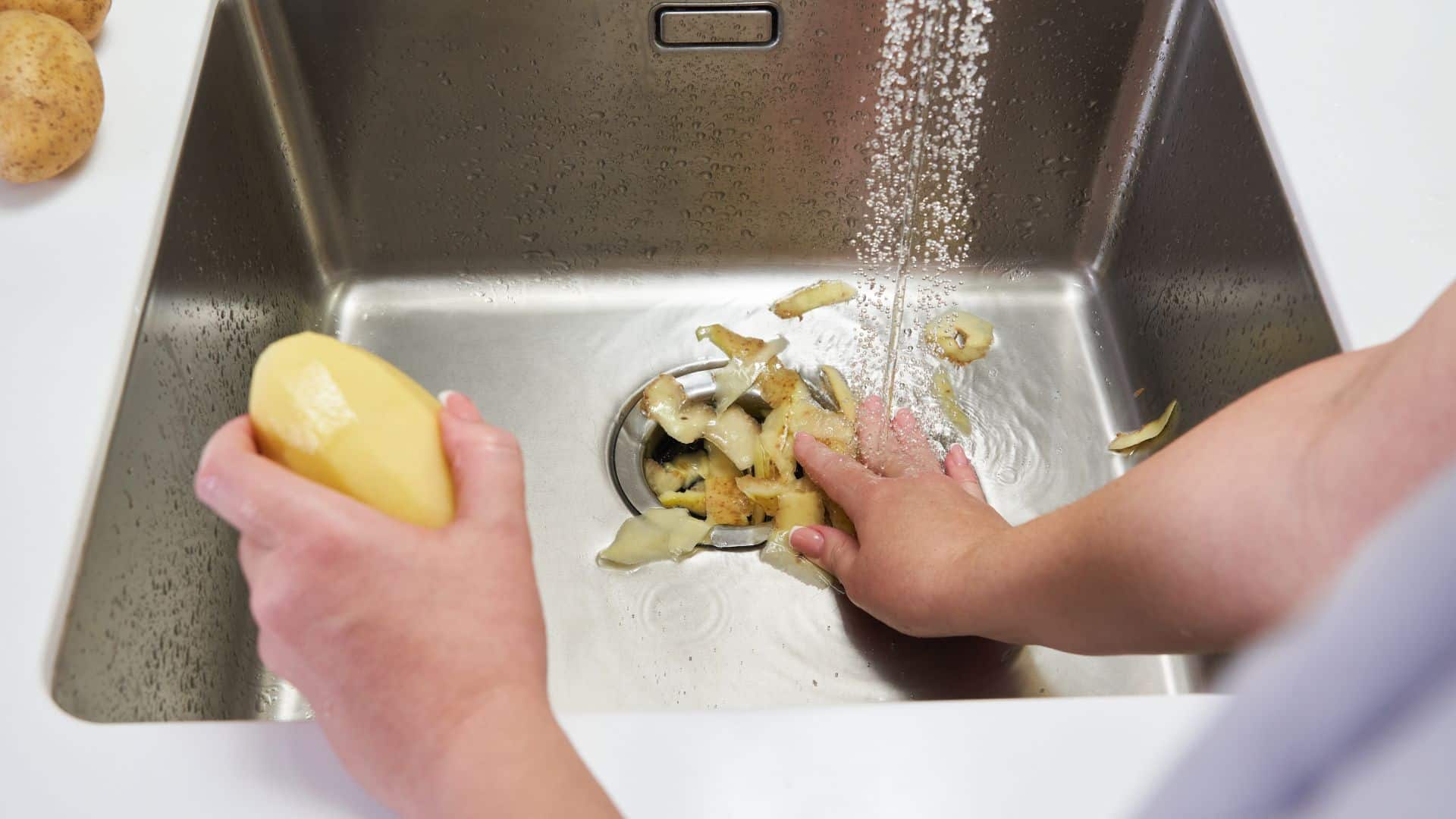 person putting potato peels down their garbage disposal